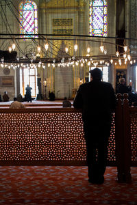 Rear view of man standing at illuminated temple in city