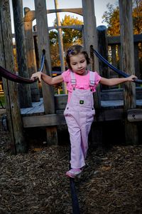 Little girl playing on wooden jungle gym at park