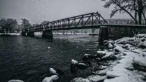 Bridge over river against sky during winter