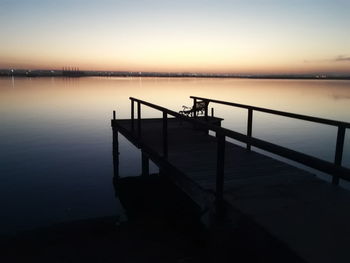 Pier on lake against sky during sunset