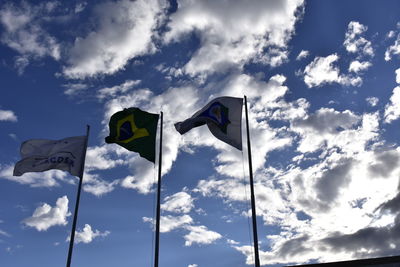 Low angle view of flags against cloudy sky