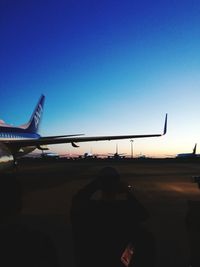 Airplane flying over airport runway against clear sky