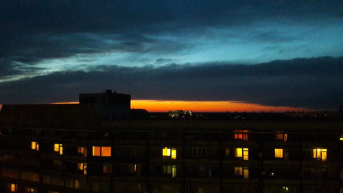 Illuminated buildings against sky at sunset