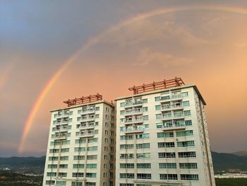 Low angle view of rainbow over building against sky