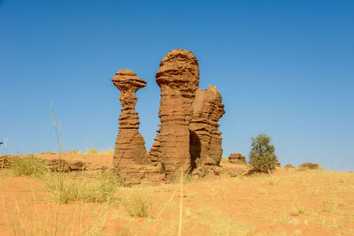 Rock formations on landscape against clear blue sky