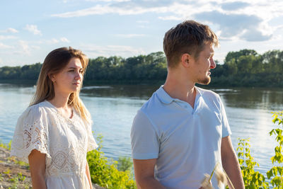 Young man and woman standing by lake