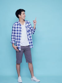 Young man looking away against blue background