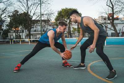 Full length of men playing basketball outdoors