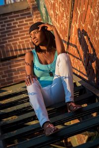 Low angle view of young woman looking away while sitting on steps