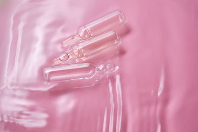 Ampoules in water on a pink background.