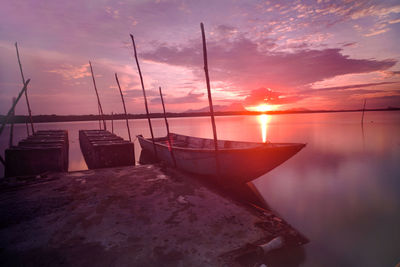 Sailboats moored on sea against sky during sunset