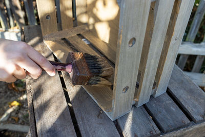 A child paints a wooden box with brushes in the garden