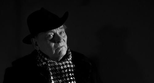 Portrait of senior man wearing hat against black background