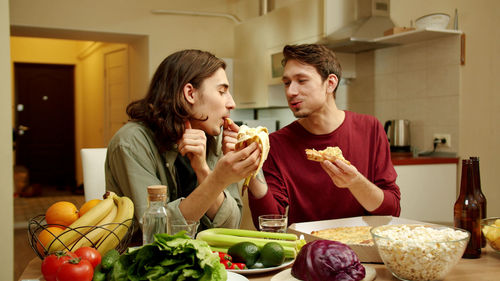 Young couple eating food in kitchen at home