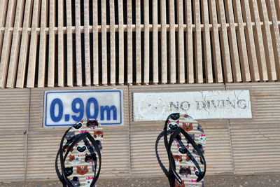 Close-up of pool depth sign on pool side with flip-flops.