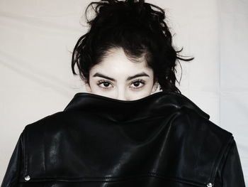 Portrait of woman hiding behind leather jacket