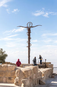 Rear view of people on cross against sky