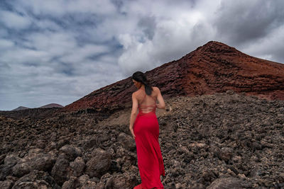 Rear view of woman on rock against sky