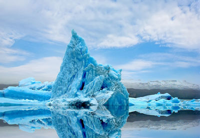 Close-up of ice crystals against blue sky during winter