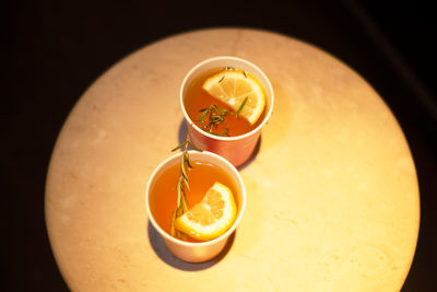 Two cups of tea with lemon and rosemary on a round table. view from above.