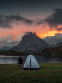 Rear view of man on lake against sky during sunset