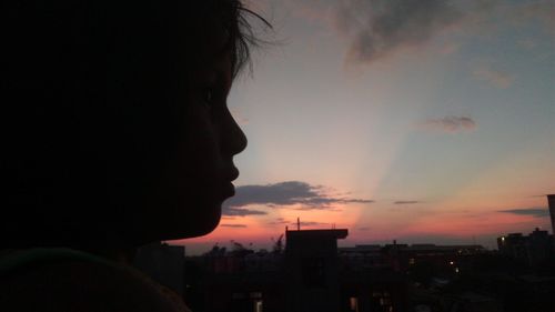 Close-up portrait of silhouette man against cityscape during sunset