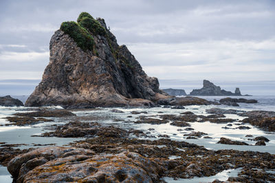 Rock formation on sea shore against sky