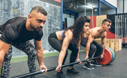 Men and woman performing dead lift at gym