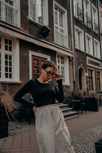 Young woman standing against building