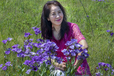 Portrait of smiling woman with purple flower in field