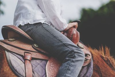 Midsection of woman horseback riding