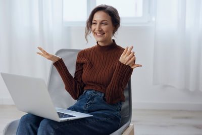 Portrait of young woman sitting on sofa at home