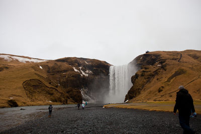 People visiting skogafoss against sky