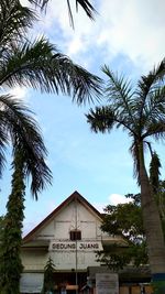 Low angle view of palm trees and building against sky