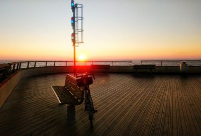 Pier by sea against clear sky during sunset