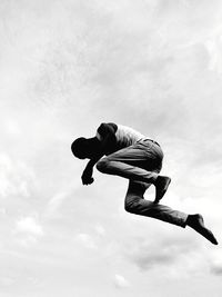 Low angle view of man jumping against sky