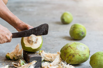 Midsection of man cutting coconut 