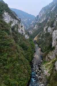 Scenic view of waterfall amidst mountains against sky