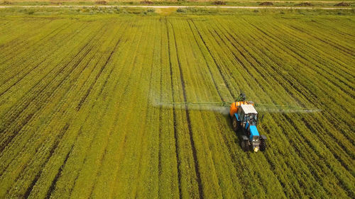 Aerial view tractor spraying the chemicals on the large green field. 