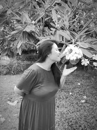 Young woman holding flower while standing on field