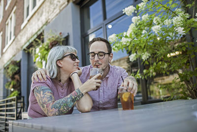 Young couple sitting in outdoor cafe drinking ice tea