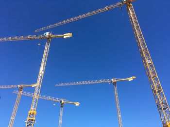 Low angle view of crane against clear blue sky