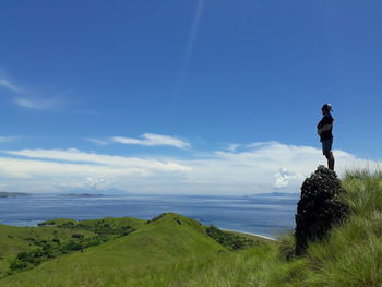 Side view of man standing on mountain against sea