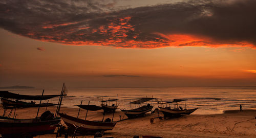 Boats moored at shore against sky during sunset