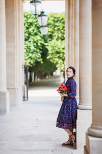 Portrait of elegant woman in a blue dress posing next to a city building