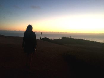 Rear view of woman photographing sunset on beach