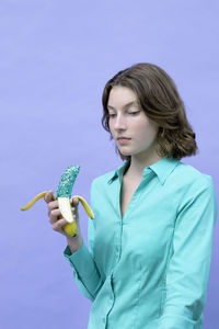 Serious girl holding glittered banana against lavender background