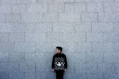 Portrait of young man standing against wall