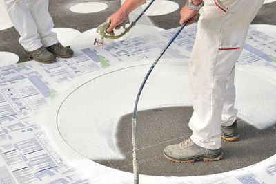 Low section of people spray painting floor