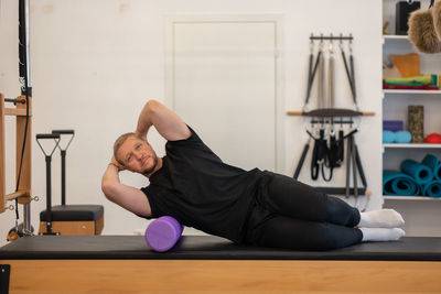 Male fitness pilates trainer shows exercises on special simulators. pilates stretch tables